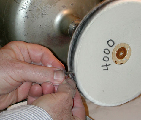 Jeweler finishing the four-prong, platinum solitaire on the 4000 grit abrasive wheel