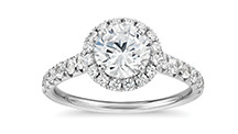 这张图片展示一颗钻石被一圈米粒钻环绕的订婚戒指。