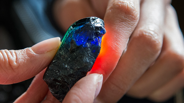 Hands holding a piece of sapphire rough