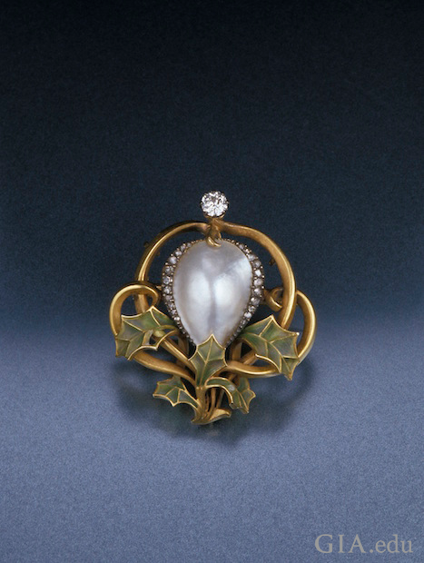 A blister pearl in the center, framed by diamonds and framed on the bottom with green enamel leaves.