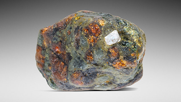 Figure 1. Mantle eclogite xenolith (2.8 cm in longest dimension) consisting of clinopyroxene (green) and garnet (red-orange), with a partially exposed octahedral diamond. Photo by Annie Haynes. Gift of Mark Mauthner, GIA Museum no. 37511.