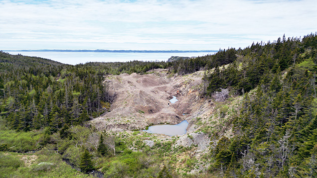 Figure 2. View of the amethyst-bearing trench looking west-southwest into Placentia Bay. The vein is exposed in the right side of the trench, and overburden is displaced to the left. Aerial drone photo by Philippe Belley.