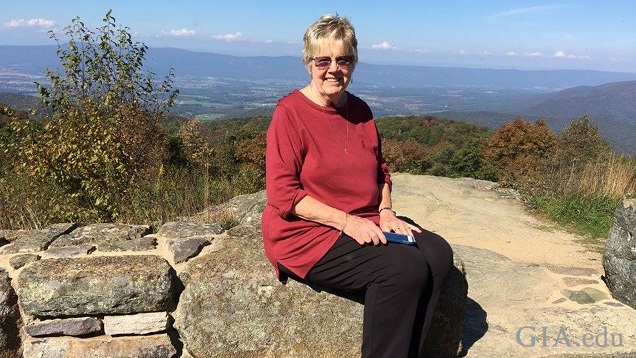 A woman sits on some rocks with a Smokey Mountain vista behind her.