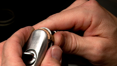 Close up of a jeweler holding a ring clamp 
