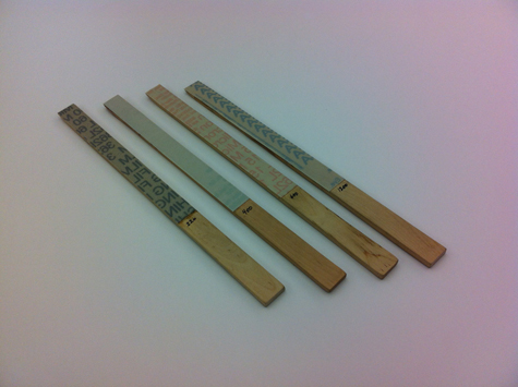 Four pieces of micro-finishing film wrapped around sanding sticks