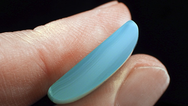 Cross-section of chalcedony cabochon shows blue mantle zoning.