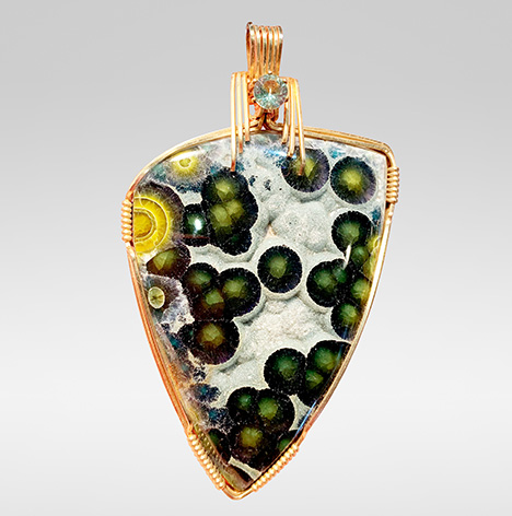 A 150 ct wavellite cabochon wrapped in gold-plated wires.