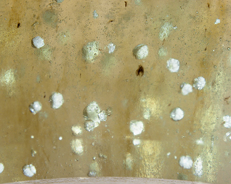 Figure 3. White spherulites in the bangle were identified as cristobalite by Raman analysis. Photomicrograph by Sze Ling Wong; field of view 5.98 mm.