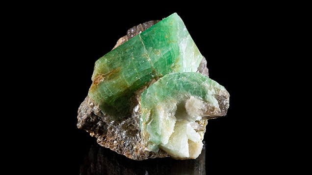 Figure 2. <em>In situ</em> emerald and beryl from Newfoundland. The primary crystal shows a lively green hue. The crystal on the lower right shows strong concentric zonation with a green rim and a white core. Photo by Emma Hutchinson Photography; courtesy of Art Gardner.