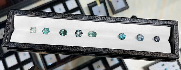 Figure 1. Untreated Montana sapphire showing a variety of cuts and the range of in-demand green to blue hues available. The stones range in size from 3.34 ct (stone on the far right) to 5.78 ct (third from the left). Photo by Jennifer Stone-Sundberg; courtesy of Obsessed Over Gems.