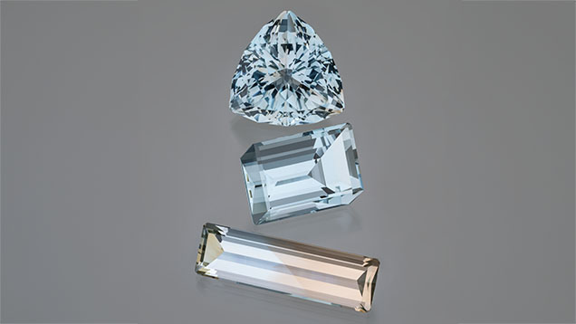 Figure 2. Exceptionally large and clean blue and bicolor topaz from the Volyn deposit. The blue triangular cut is 113.86 ct, the middle blue cube cut is 87.82 ct, and the blue and golden bicolor rectangular cut is 55.70 ct. Photo by Robert Weldon; courtesy of Dudley Blauwet Gems.