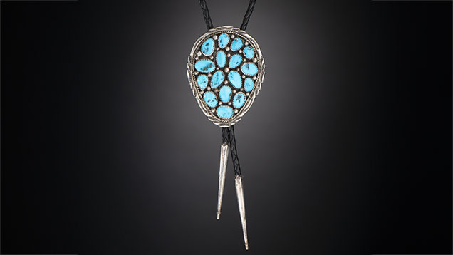 Figure 9. Vintage Navajo silver bolo tie with turquoise reportedly from the Morenci mine in southeastern Arizona, which is not currently being mined for turquoise. This highly collectible material, known for its desirable blue color and iron pyrite matrix, dates back to 1864 and was a byproduct of copper mining. Photo by Kevin Schumacher; courtesy of Aaron Palke.