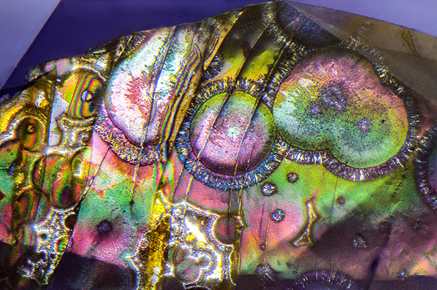 Radial limonite within a surface-reaching fracture of a violet sapphire shows bright interference colors when viewed under diffused reflected light. Photomicrograph by Nathan Renfro; field of view 1.44 mm.