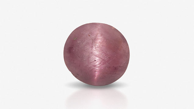 Figure 1. This 0.50 ct purplish pink cabochon is a rare chatoyant example of hexagonite. Photo by Jian Xin (Jae) Liao.