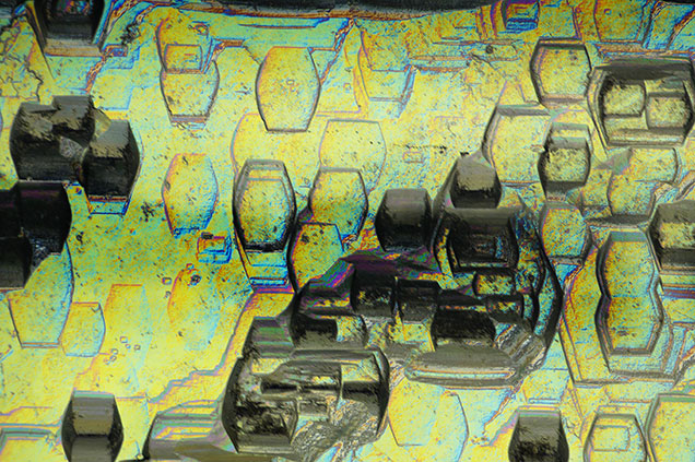 Figure 2. Heliodor viewed with differential interference contrast filters. Compressed hexagonal etch features exist on every prismatic face and run the length of the crystal. Photomicrograph by Rhiana Henry; field of view 2.88 mm.