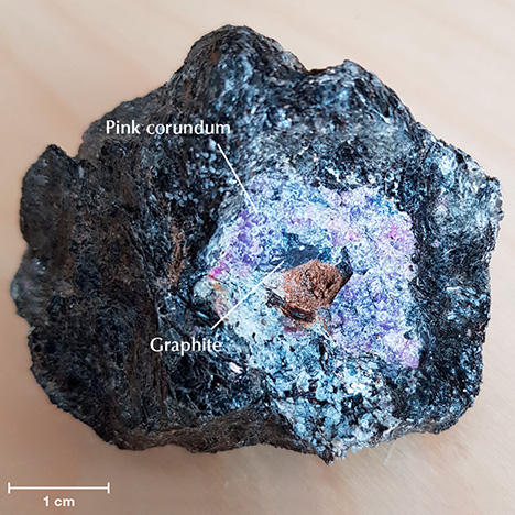 Pink corundum with a graphite inclusion.