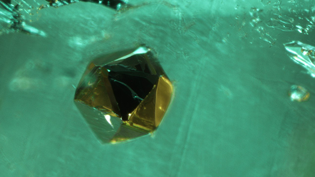 A pseudo-icosahedral crystal of pyrite in a 2.88 ct Colombian emerald. Photomicrograph by Taku Okada; field of view 1.01 mm.