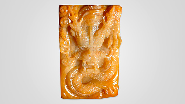 Figure 1. Chalcedony petrified tree fern is carved as an ornamental gem material. This 60 × 40 mm dragon carving has a uniform texture and bright color. Photo by Hai-Long Wang.