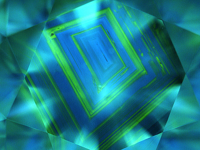 Figure 14. Natural type Ia diamonds often show a growth pattern that has been compared to the growth rings of a tree. However, it is not as common to see the alternating pattern of blue fluorescence (due to the N3 center) and green (due to H3/H4 centers) shown in this 1.83 ct K-color diamond with SI2 clarity. PL spectroscopy is very useful for confirming these centers and for detecting much weaker optical centers. Image by GIA staff.