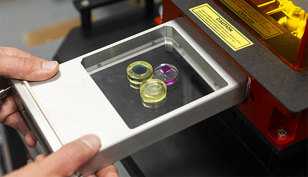 Figure 4. LA-ICP-MS analyses are standardized with NIST glass standard reference material (the blue and colorless pieces in yellow epoxy) for a variety of elements. Also shown is our internally developed matrix-matched corundum standard (colorless epoxy with four variously colored sapphires) used specifically for ruby and sapphire analysis. Photo by Kevin Schumacher.